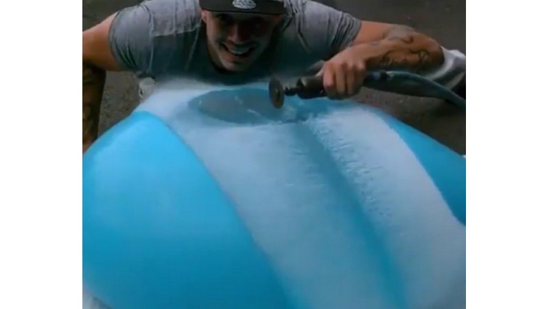 Un globo lleno de agua y una sierra a cámara lenta